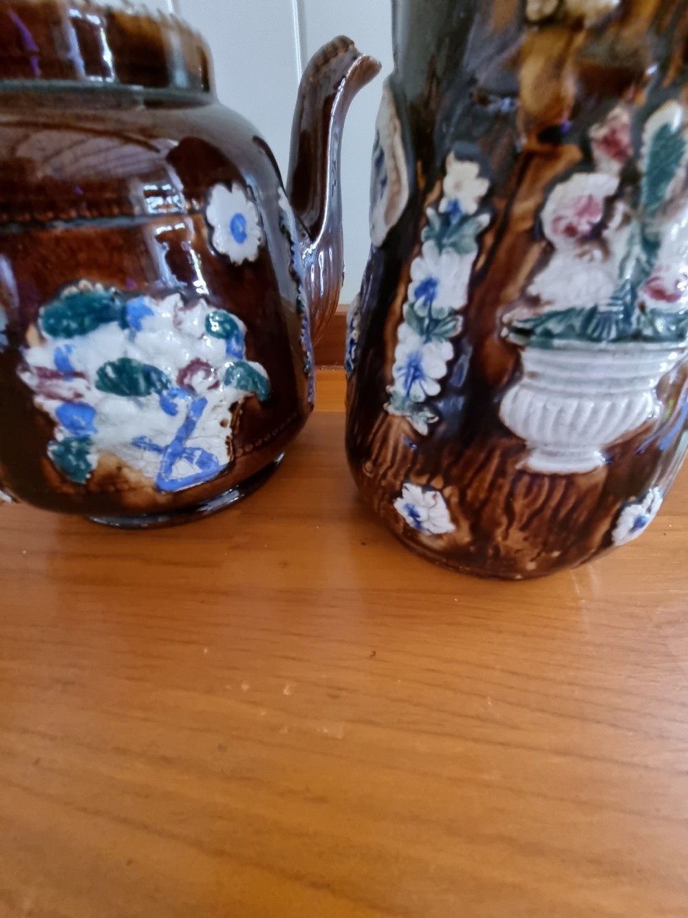 A pair of Victorian Measham Bargeware stoneware vessels, including a teapot inscribed A Present From Woodville and a jug inscribed Mrs C Drake 1893, both featuring dark brown treacle glaze and sprigged floral decoration. View VI
