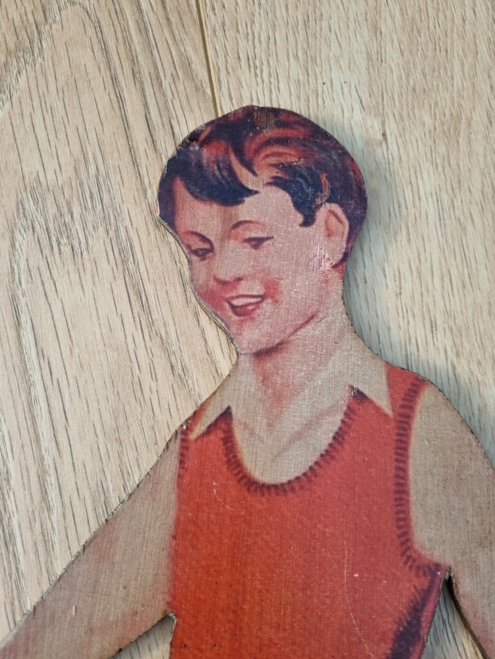 A vintage cardboard counter display sign shaped as a lying boy advertising Dinky Toys. View II