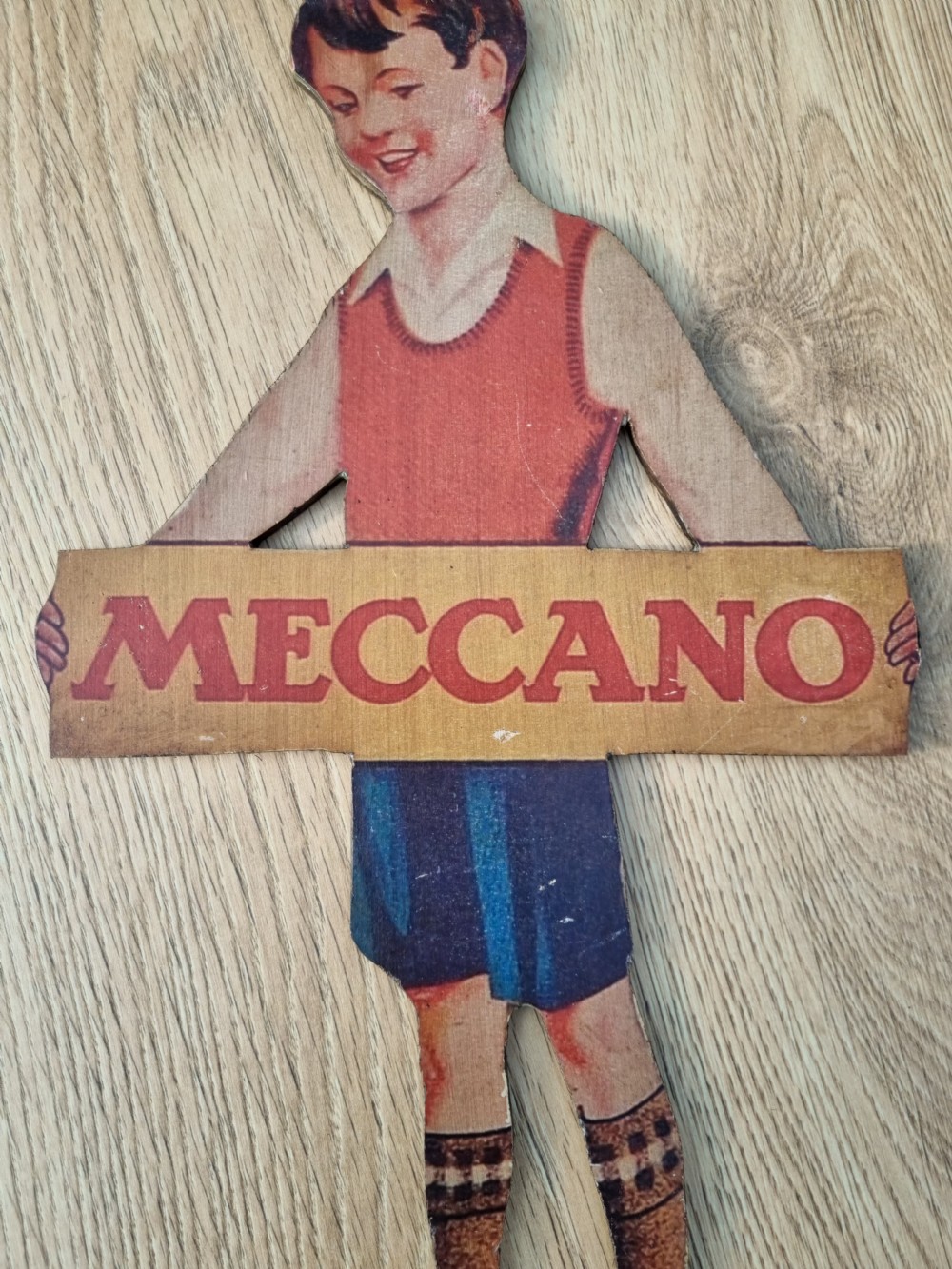 A vintage cardboard counter display sign shaped as a lying boy advertising Dinky Toys. View III