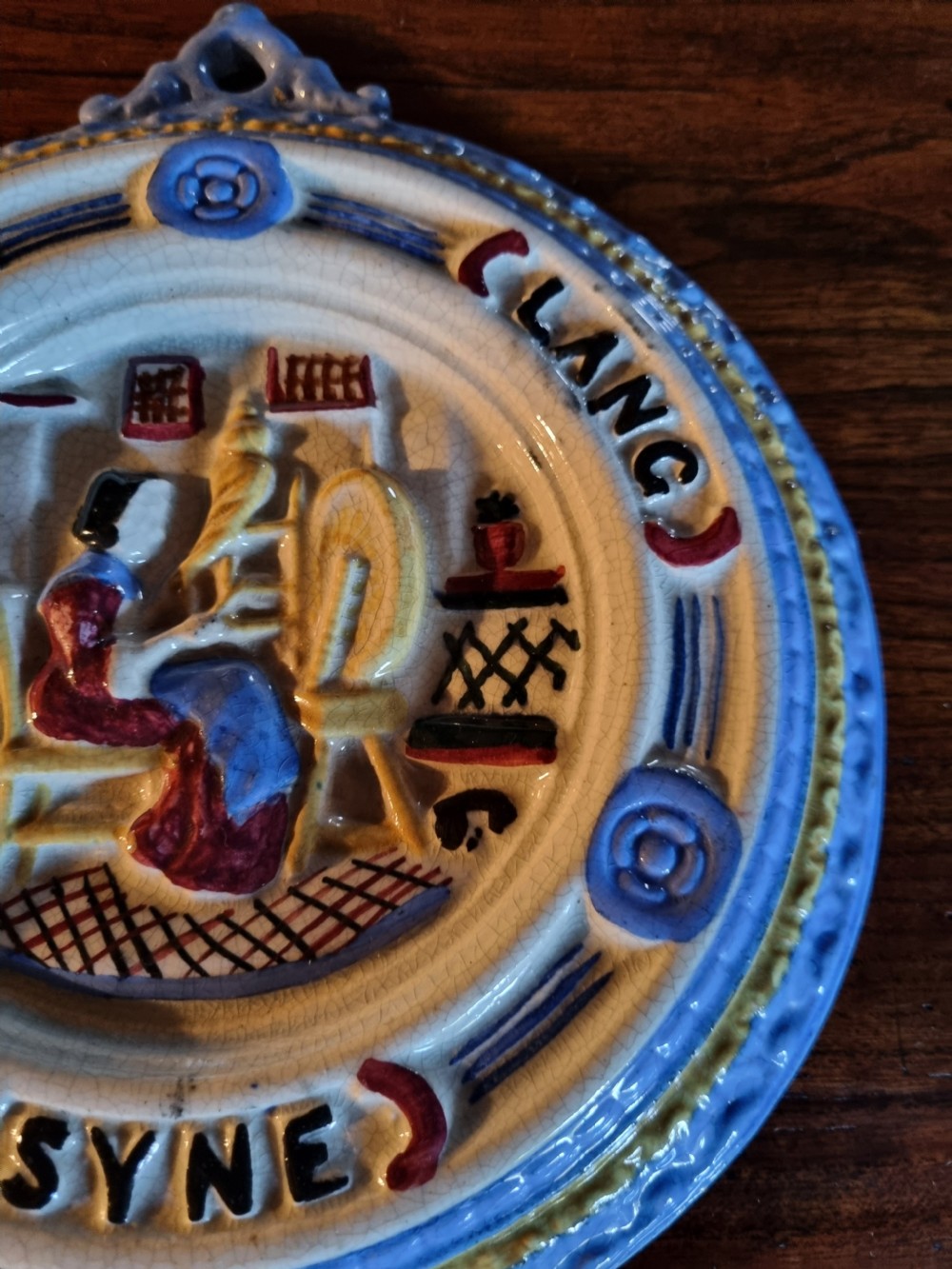 A circular nineteenth-century Scottish ceramic plaque with relief-moulded figures, lettering reading Cauld Lang Syne, and a blue and yellow glazed rim. View IV