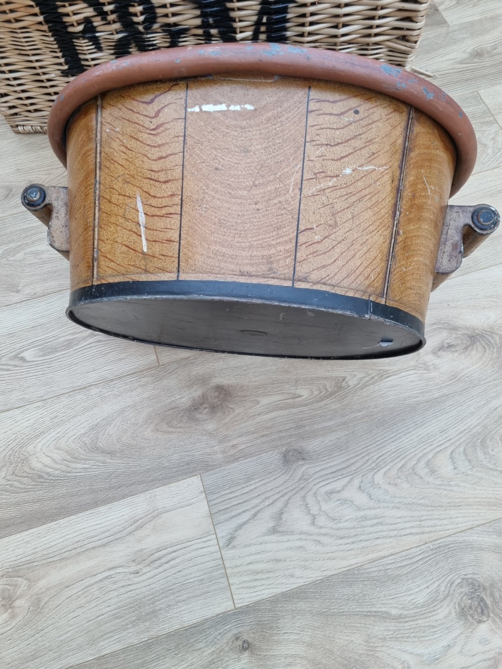 An oval nineteenth-century metal footbath featuring a hand-painted scumbled faux-wood effect, a terracotta rolled rim, and heavy side carrying handles. View VI