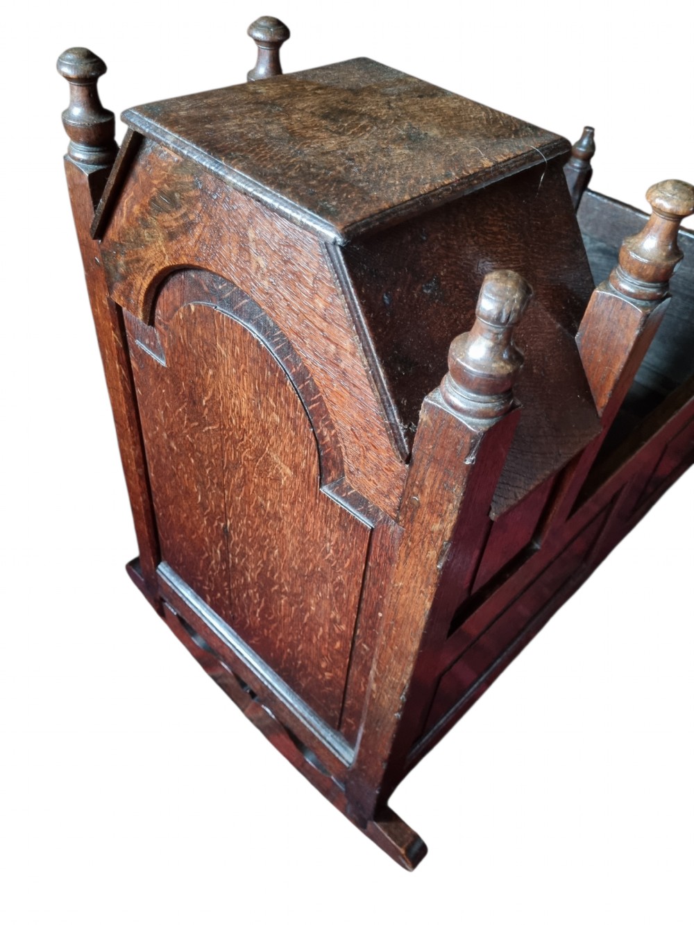 A seventeenth-century dark oak hooded cradle featuring panelled side construction, turned finials on the corner posts, and solid wooden rockers. View VI