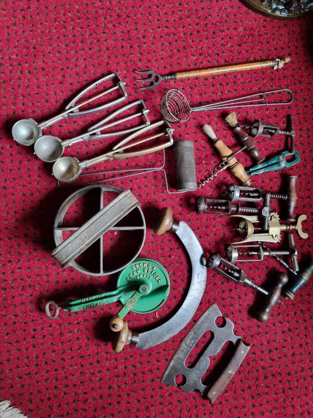 A collection of 19th-century metal kitchenalia featuring a copper colander with brass handles alongside several antique tin graters. View II