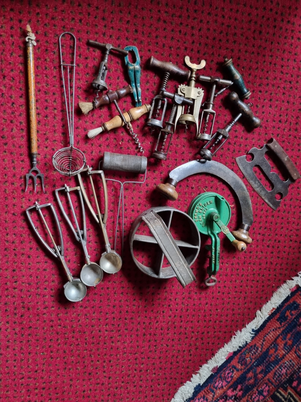 A collection of 19th-century metal kitchenalia featuring a copper colander with brass handles alongside several antique tin graters. View VII