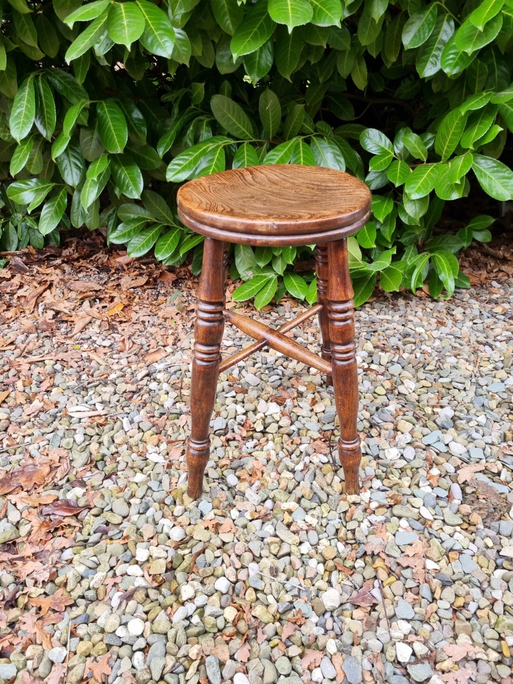 A 19th-century tall wooden stool crafted from elm, featuring a circular seat, four turned legs, and cross stretchers. View V