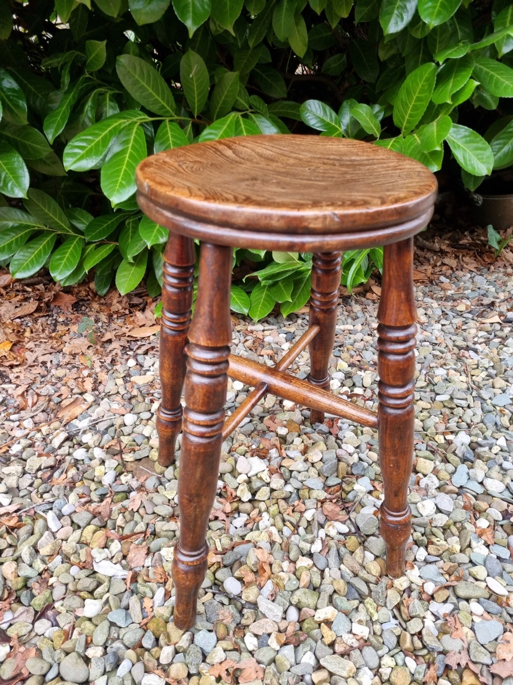 A 19th-century tall wooden stool crafted from elm, featuring a circular seat, four turned legs, and cross stretchers. View VI