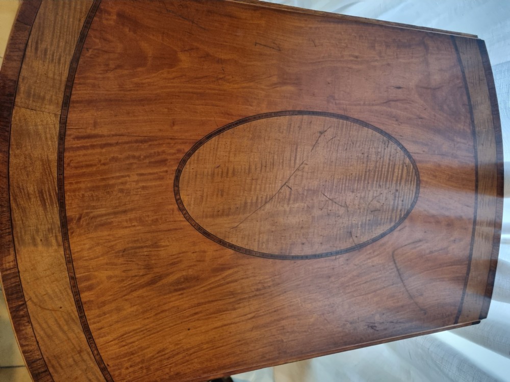 An oval Georgian drop-leaf Pembroke table crafted from inlaid satinwood with a single frieze drawer and square tapered legs on castors. View III