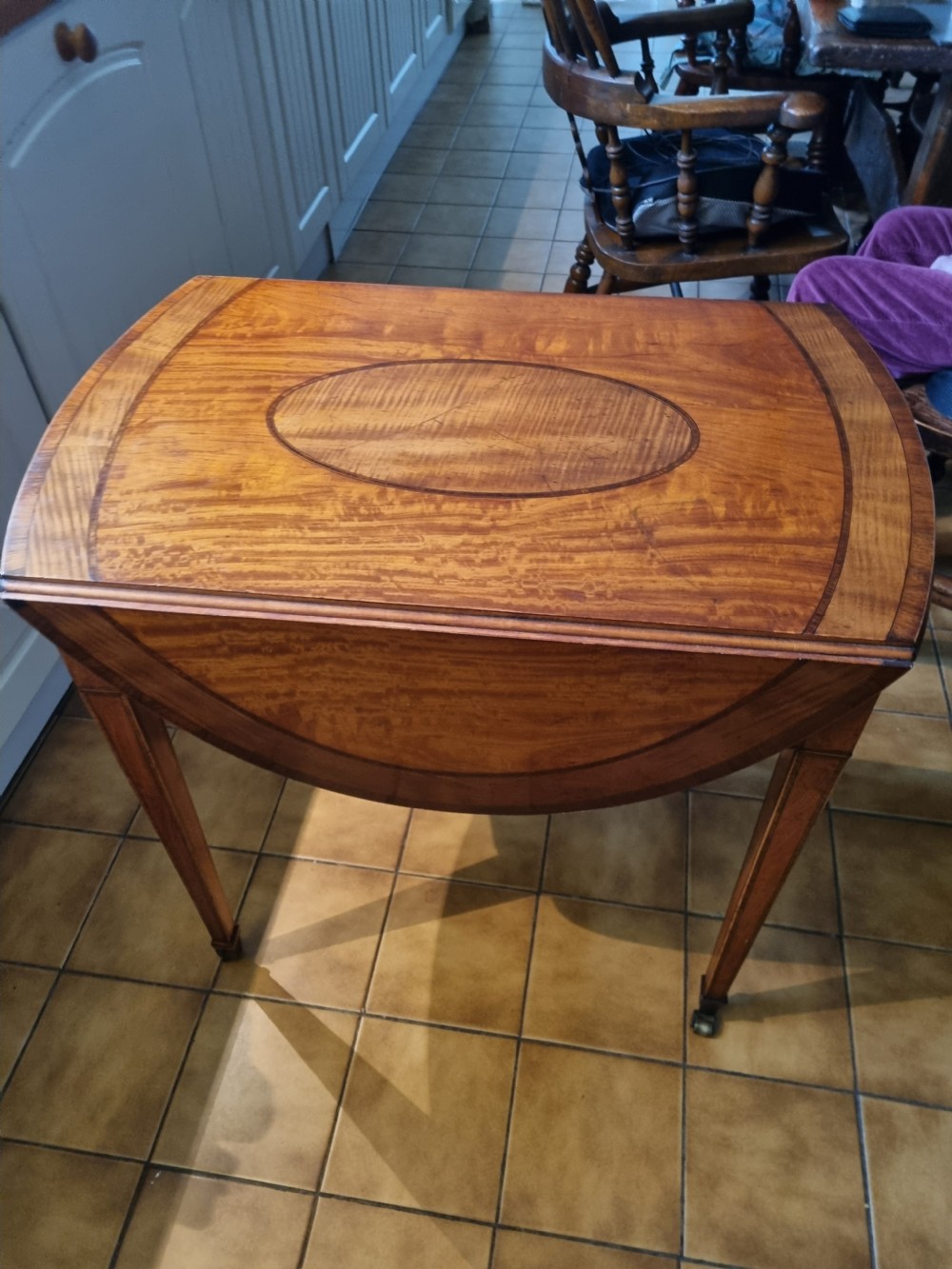 An oval Georgian drop-leaf Pembroke table crafted from inlaid satinwood with a single frieze drawer and square tapered legs on castors. View VI