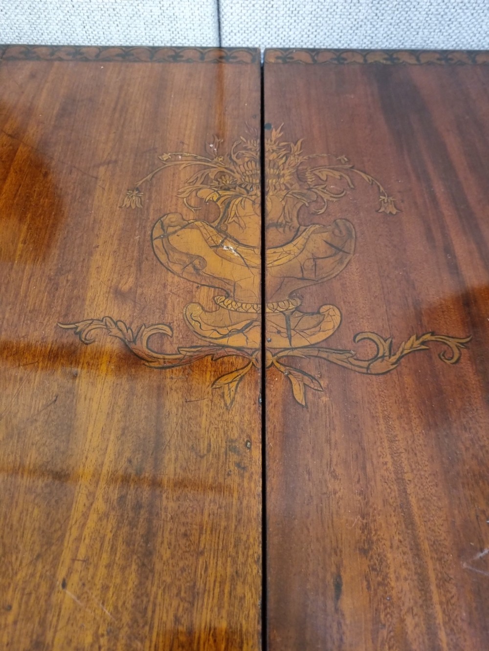 A Georgian mahogany night commode featuring intricate marquetry urn inlay on the main cupboard door, decorative floral border inlays, ceramic knobs, and a shaped base stretcher with a circular opening. View V