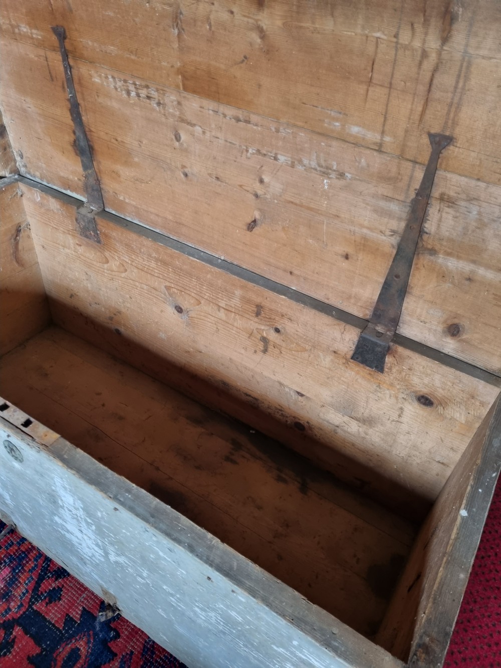 A 19th-century rectangular pine storage chest featuring weathered grey paint, iron corner bracing, metal side handles, and a flat hinged lid. View VI