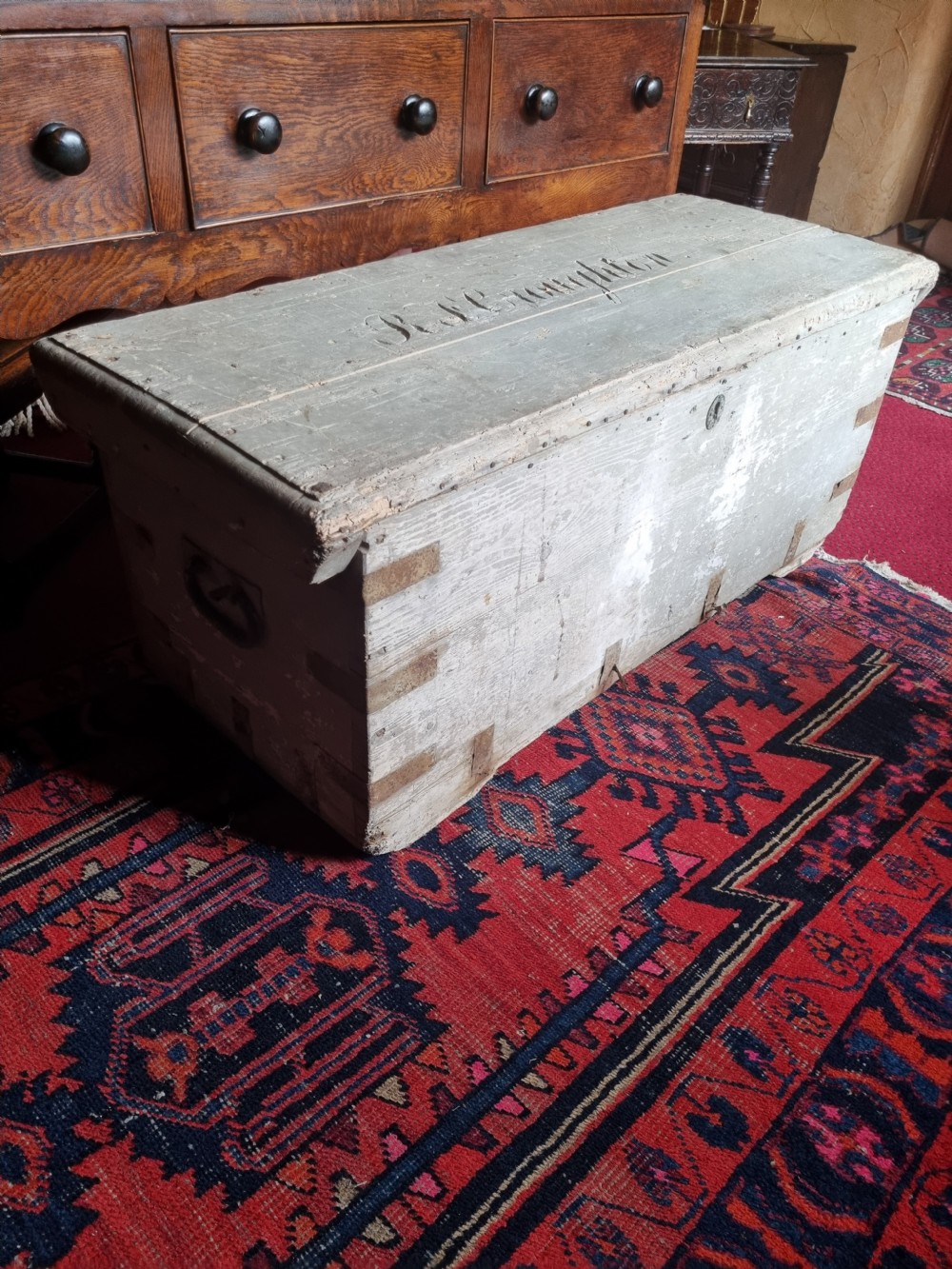 A 19th-century rectangular pine storage chest featuring weathered grey paint, iron corner bracing, metal side handles, and a flat hinged lid. View VII
