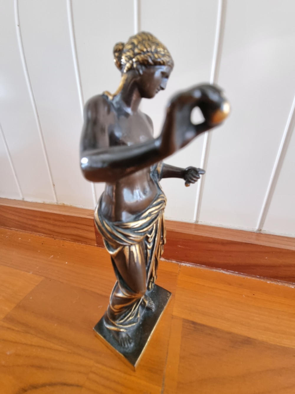 A nineteenth-century dark patinated bronze figure of Venus with draped parcel-gilded robes holding a small sphere on a rectangular base. View II