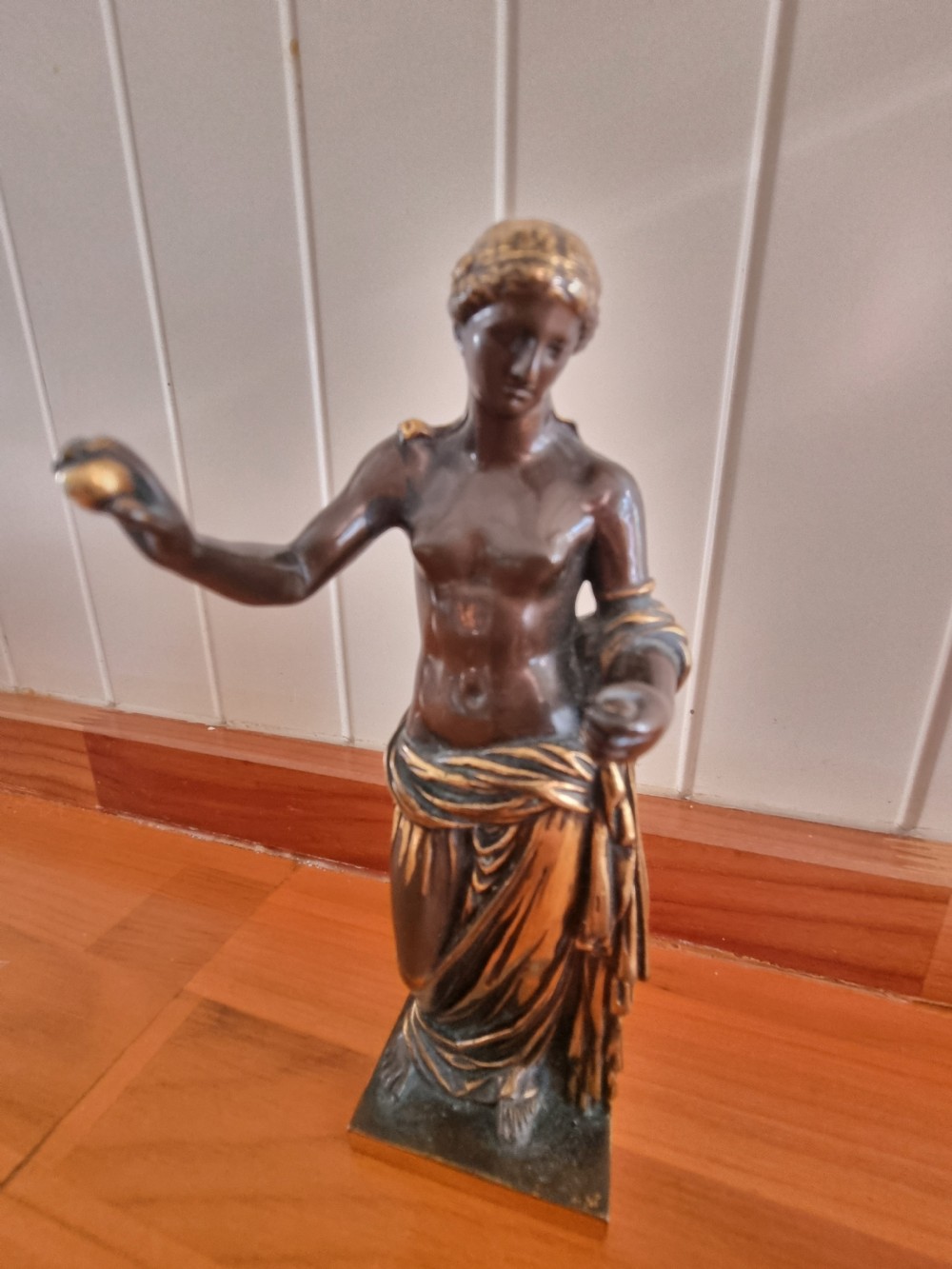 A nineteenth-century dark patinated bronze figure of Venus with draped parcel-gilded robes holding a small sphere on a rectangular base. View VI