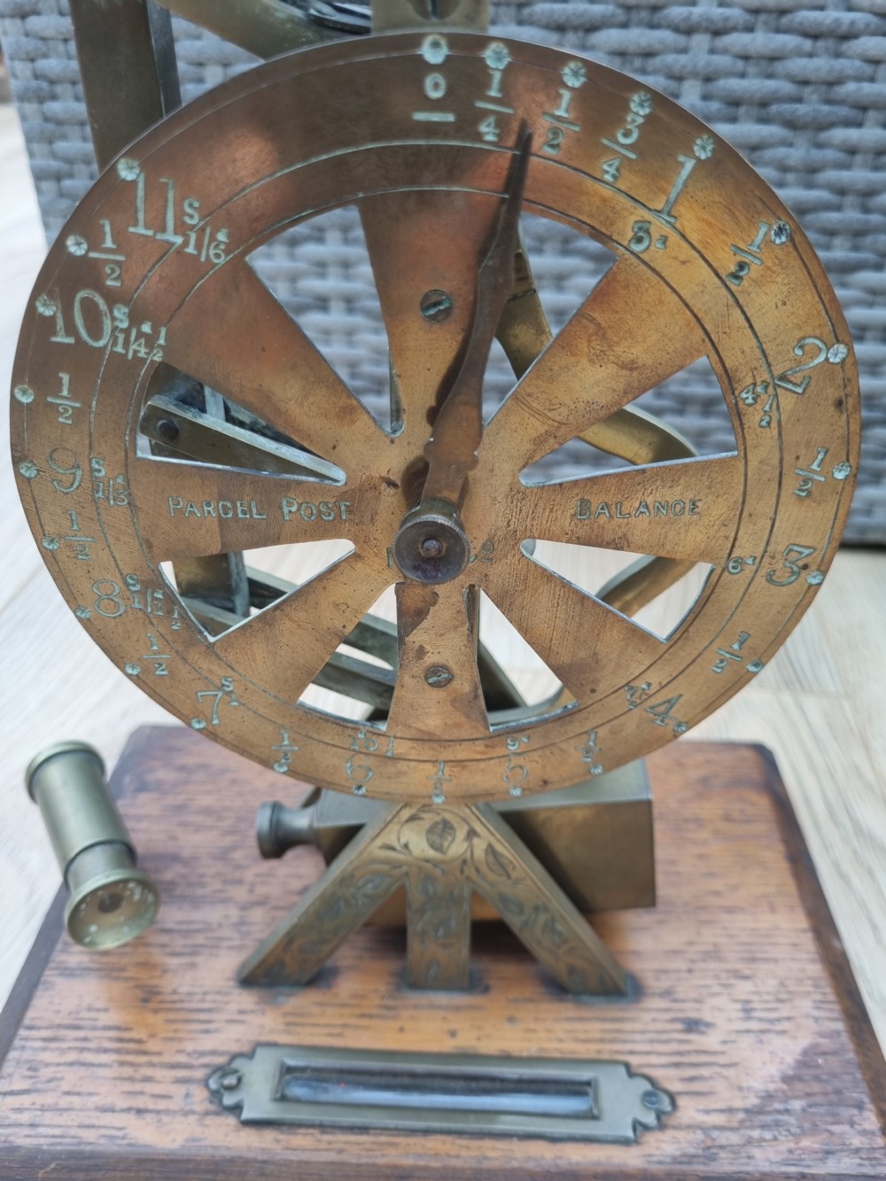 An antique brass post office parcel scale with a circular dial indicator mounted on a rectangular wooden base. View IV