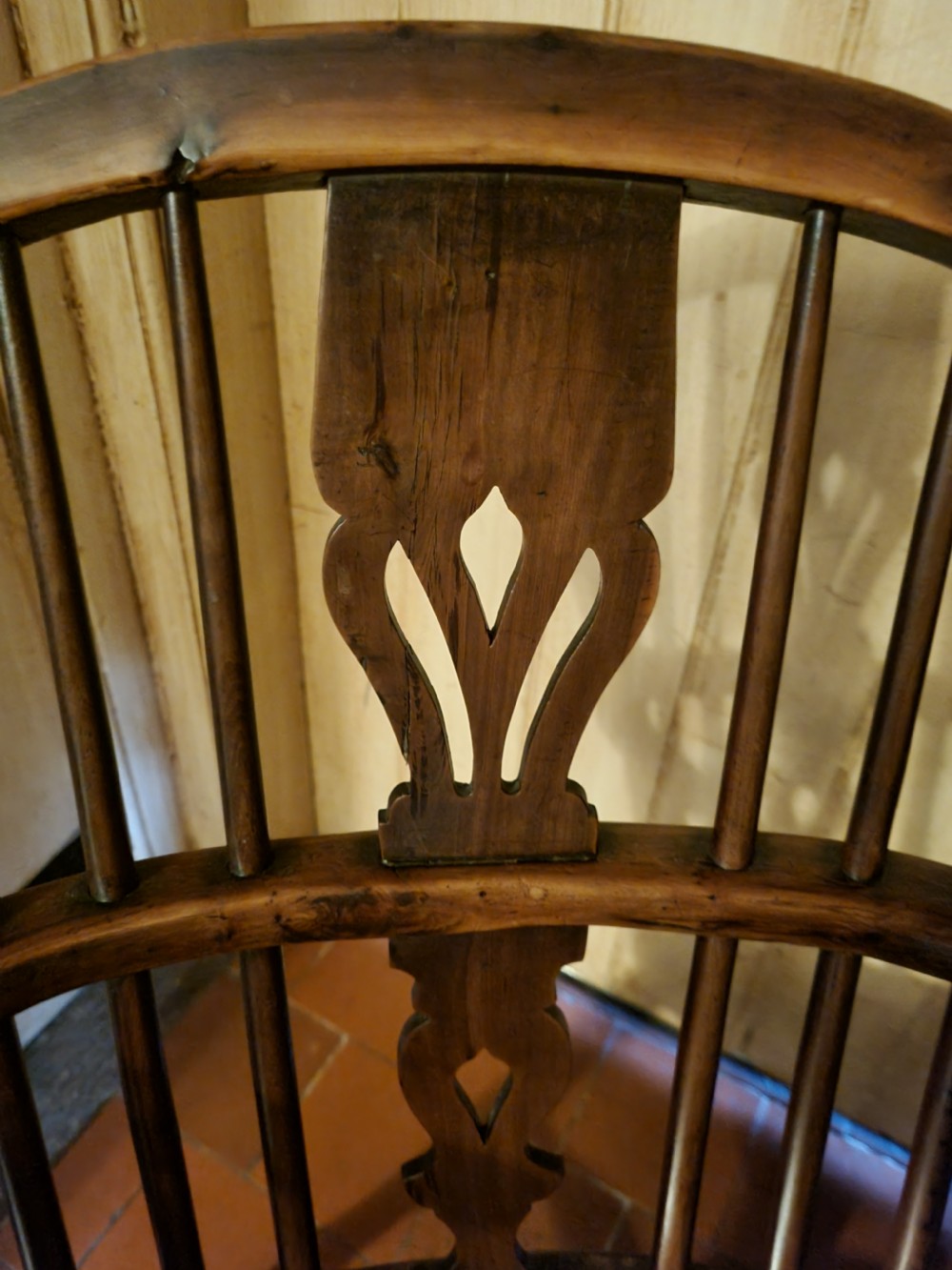 A 19th-century yew wood Windsor armchair with a hoop back, central pierced splat, turned legs, and a curved stretcher. View IV
