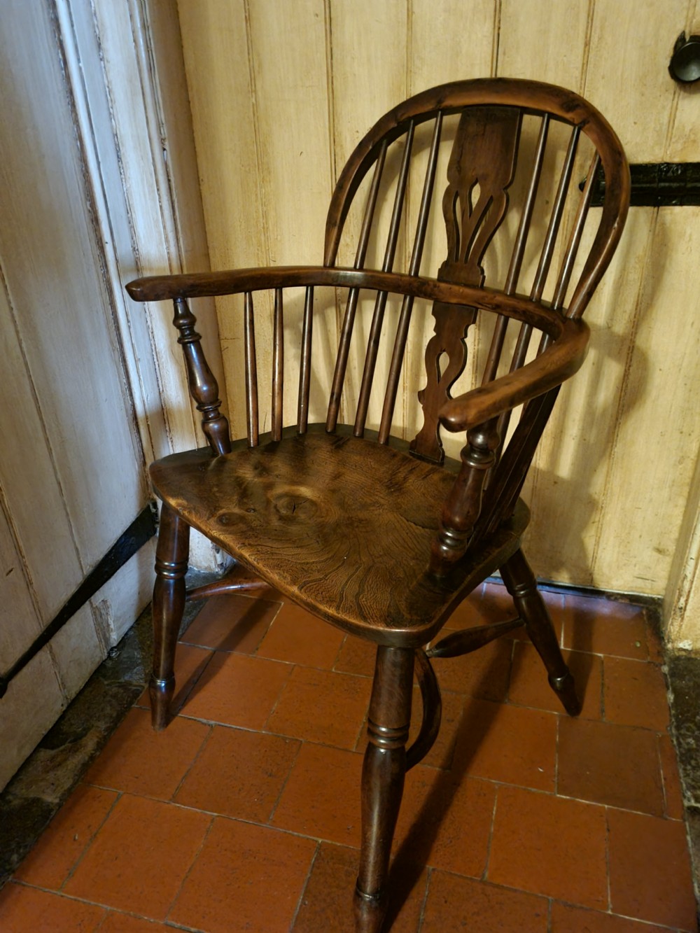 A 19th-century yew wood Windsor armchair with a hoop back, central pierced splat, turned legs, and a curved stretcher. View V