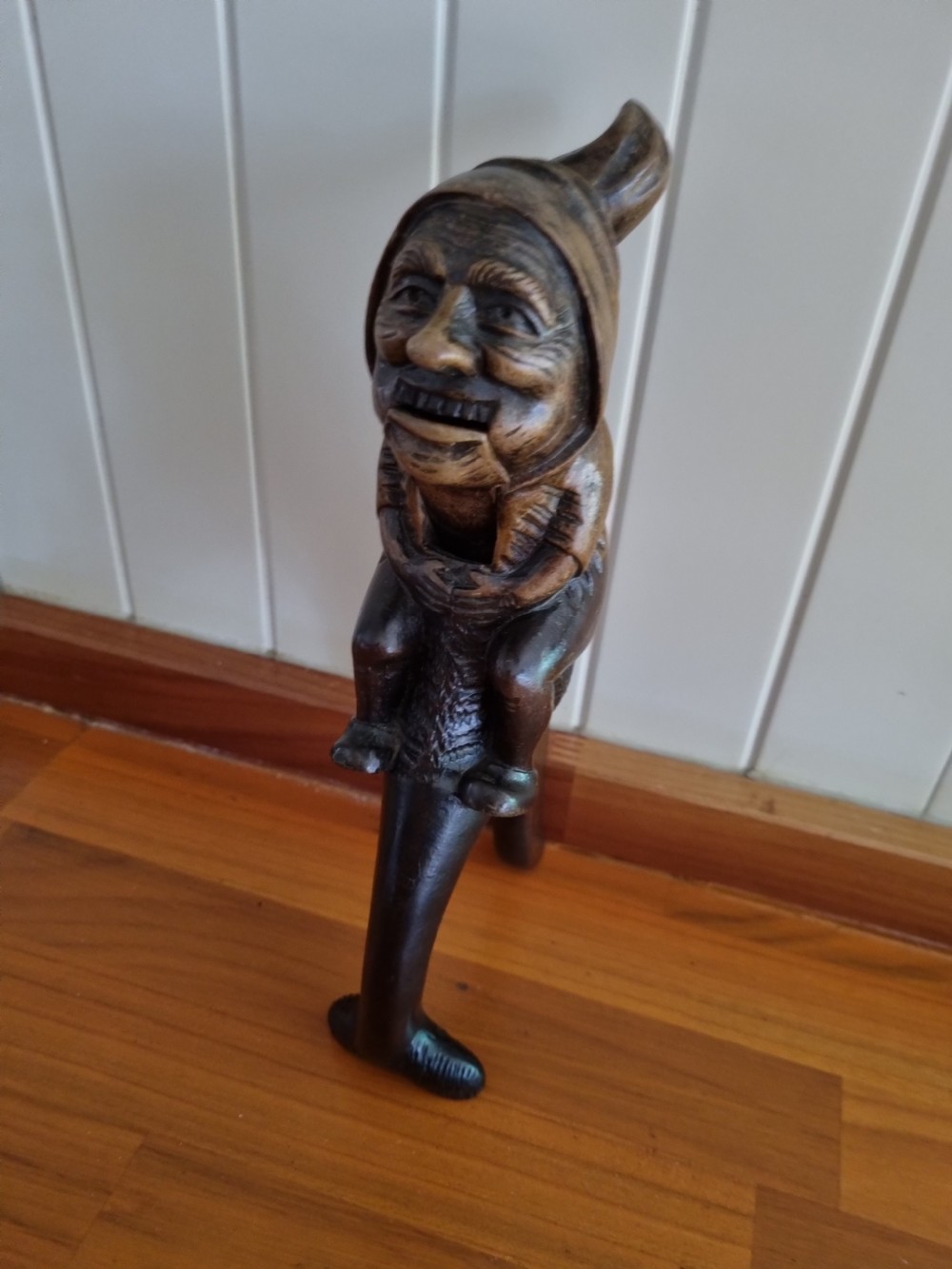 A hand-carved dark walnut nutcracker depicting a figurative hooded character with a lever mechanism. View II