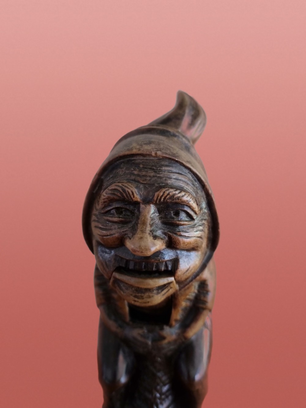 A hand-carved dark walnut nutcracker depicting a figurative hooded character with a lever mechanism. View III