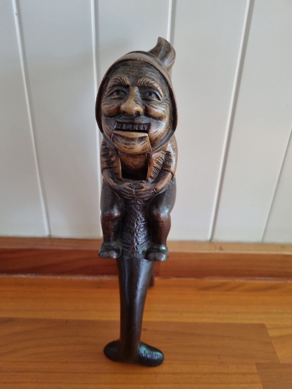 A hand-carved dark walnut nutcracker depicting a figurative hooded character with a lever mechanism. View VII