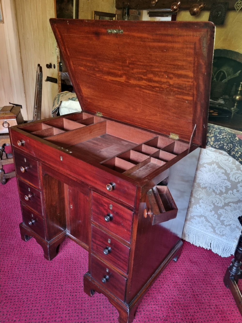 An 18th-century mahogany kneehole desk featuring a long top drawer above six smaller side drawers and a central recessed cupboard on bracket feet. View II