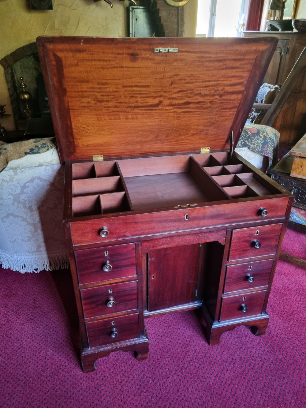 An 18th-century mahogany kneehole desk featuring a long top drawer above six smaller side drawers and a central recessed cupboard on bracket feet. View VI