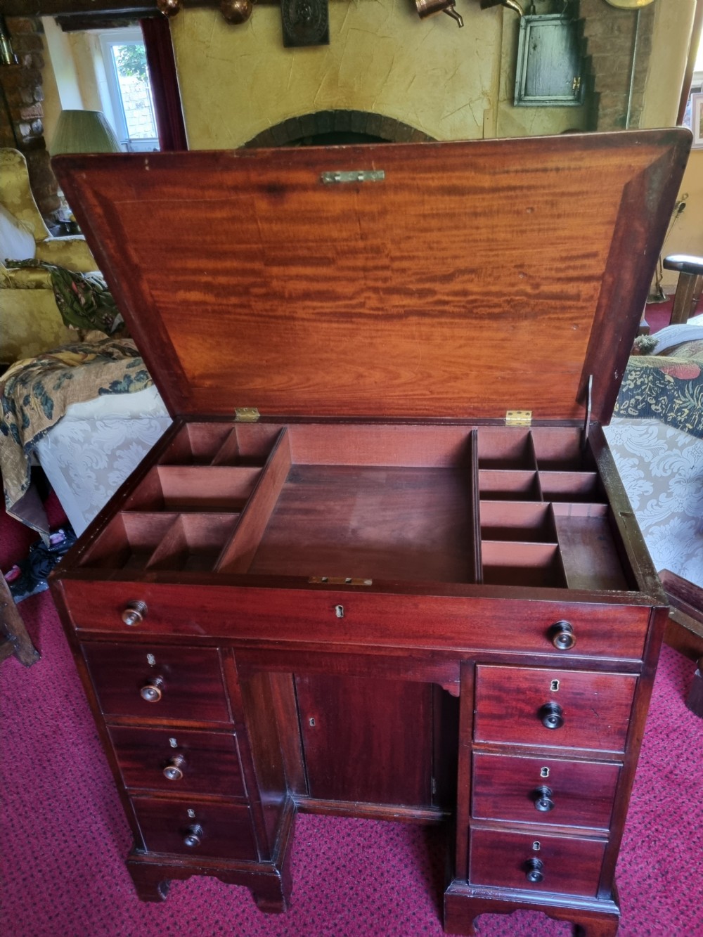 An 18th-century mahogany kneehole desk featuring a long top drawer above six smaller side drawers and a central recessed cupboard on bracket feet. View IX