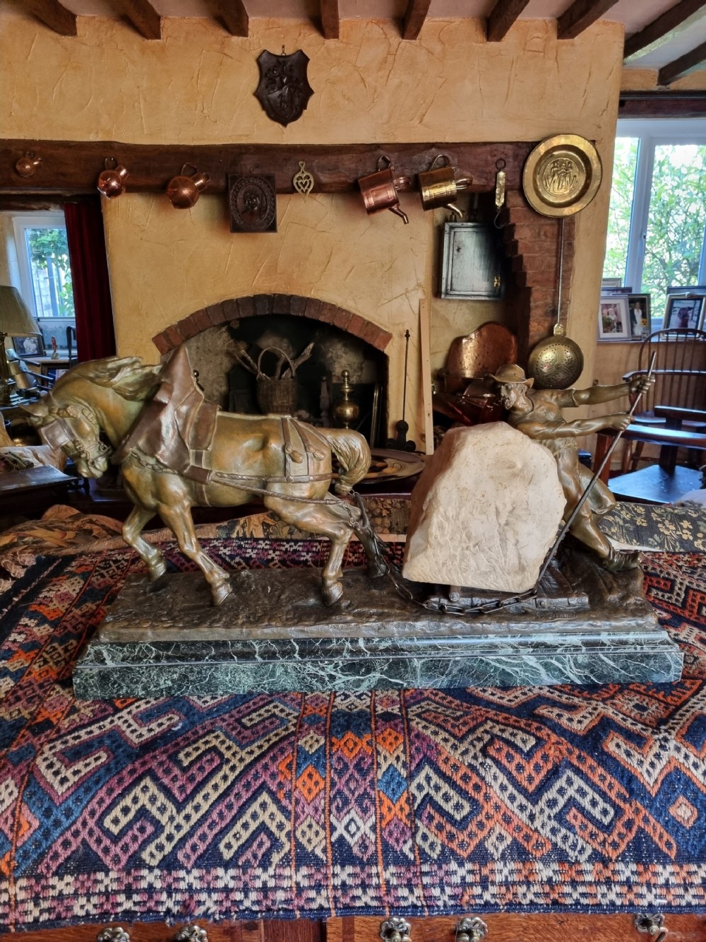 A late 19th-century patinated bronze sculpture depicting a harnessed horse pulling a stone quarry sled alongside a worker, mounted on a green marble base.