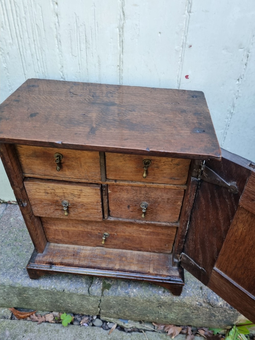 An 18th-century dark oak spice cupboard featuring a single door with a fielded raised panel and a brass oval escutcheon. View II