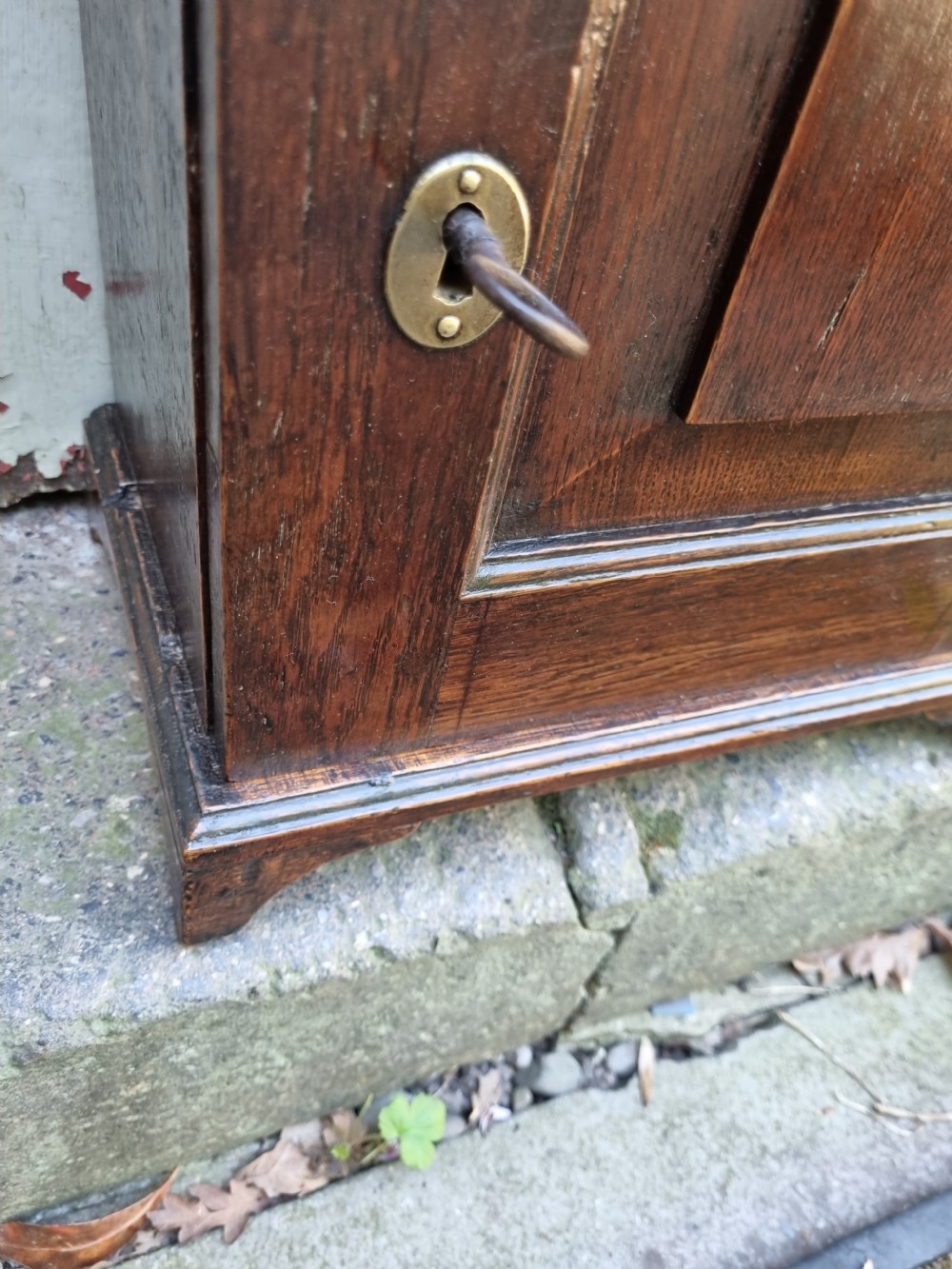 An 18th-century dark oak spice cupboard featuring a single door with a fielded raised panel and a brass oval escutcheon. View V