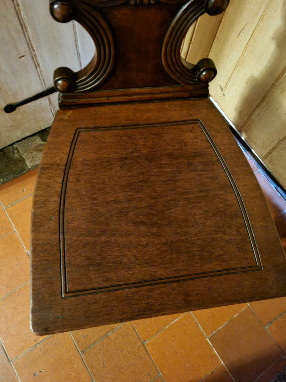 A Regency mahogany hall chair featuring an oval back panel with a central painted heraldic crest, a solid timber seat, and turned front legs. View IV