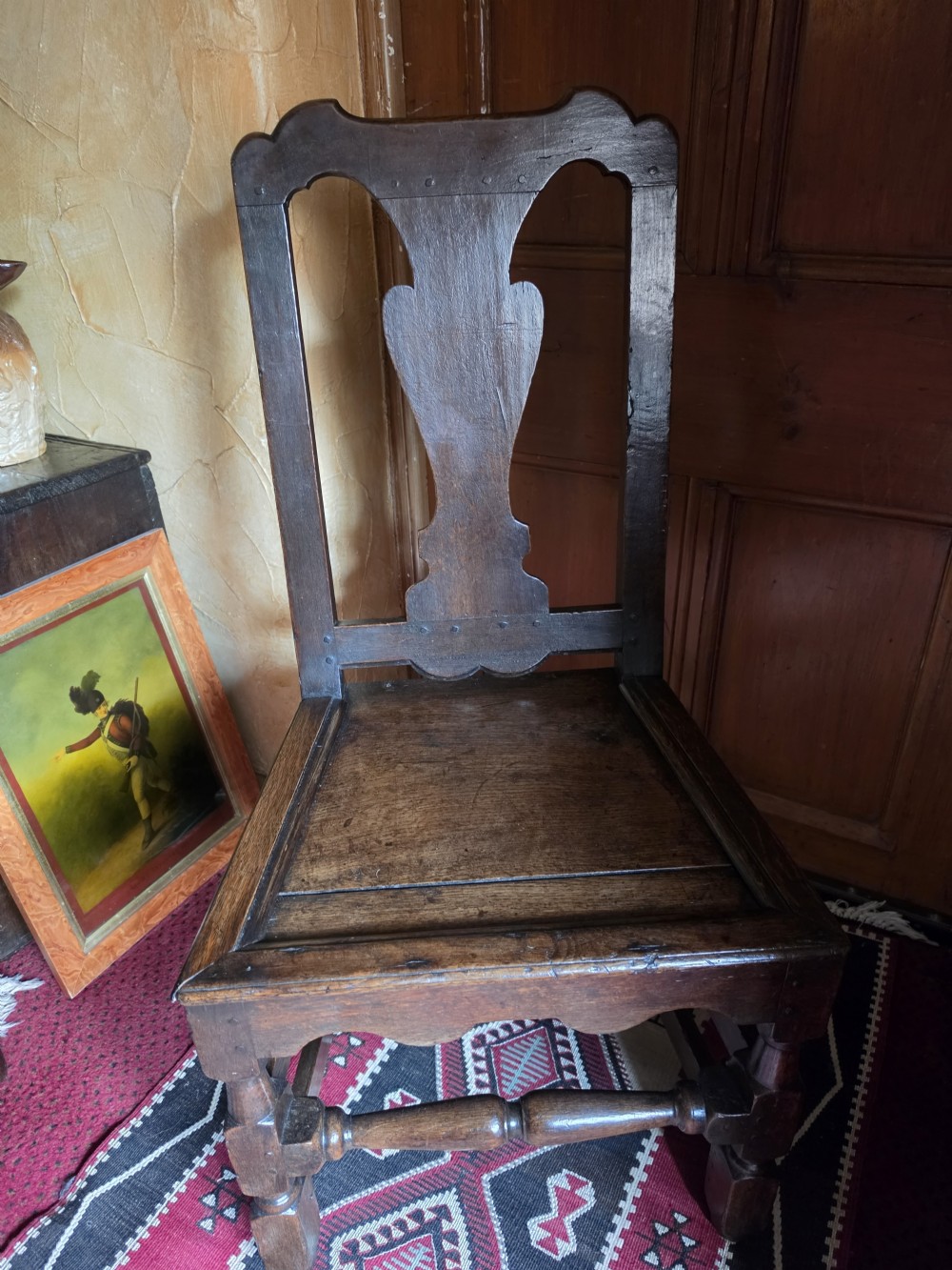 An 18th-century dark oak side chair featuring a vase-shaped splat back, solid timber seat, and turned front legs and stretcher. View IV