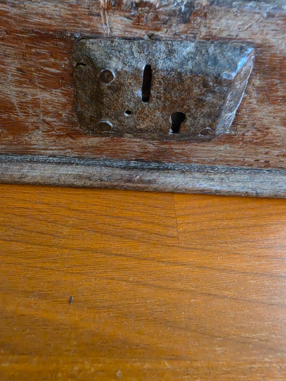 A small 17th-century style oak strong box with a hinged lid, top iron carrying handle, and heavy front wrought iron lock plate. View III