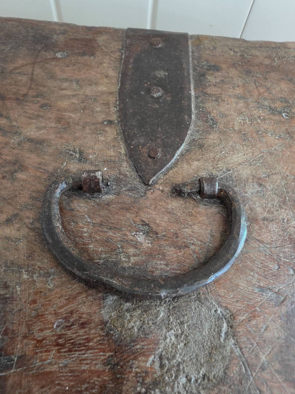 A small 17th-century style oak strong box with a hinged lid, top iron carrying handle, and heavy front wrought iron lock plate. View IV