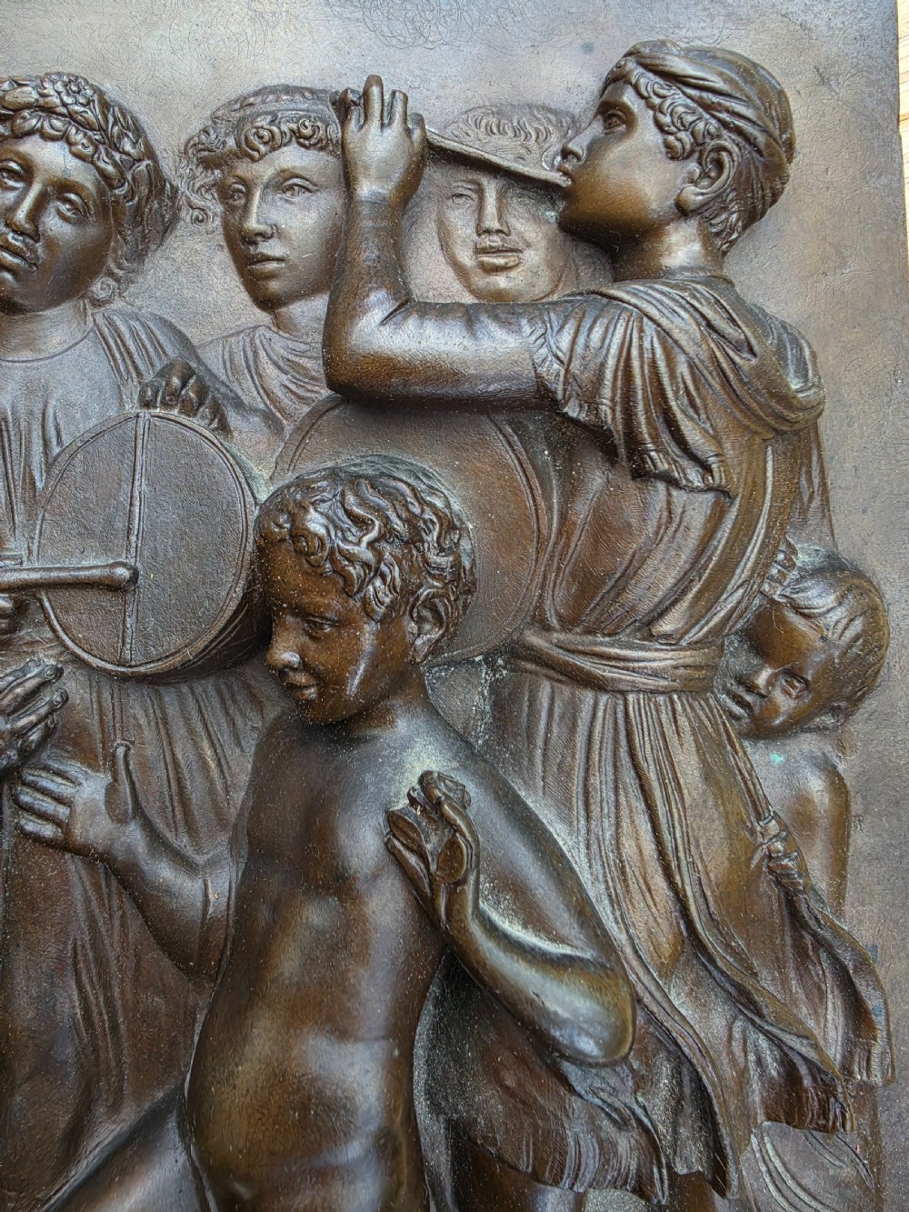 A square dark brown bronze relief plaque featuring cast figures playing musical instruments and dancing, signed F. Barbedienne at the lower right. View III