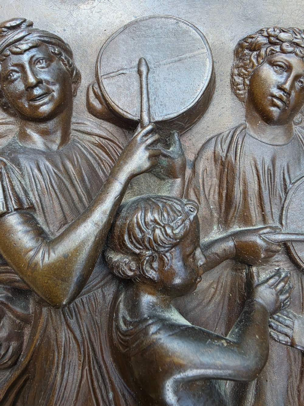 A square dark brown bronze relief plaque featuring cast figures playing musical instruments and dancing, signed F. Barbedienne at the lower right. View IV
