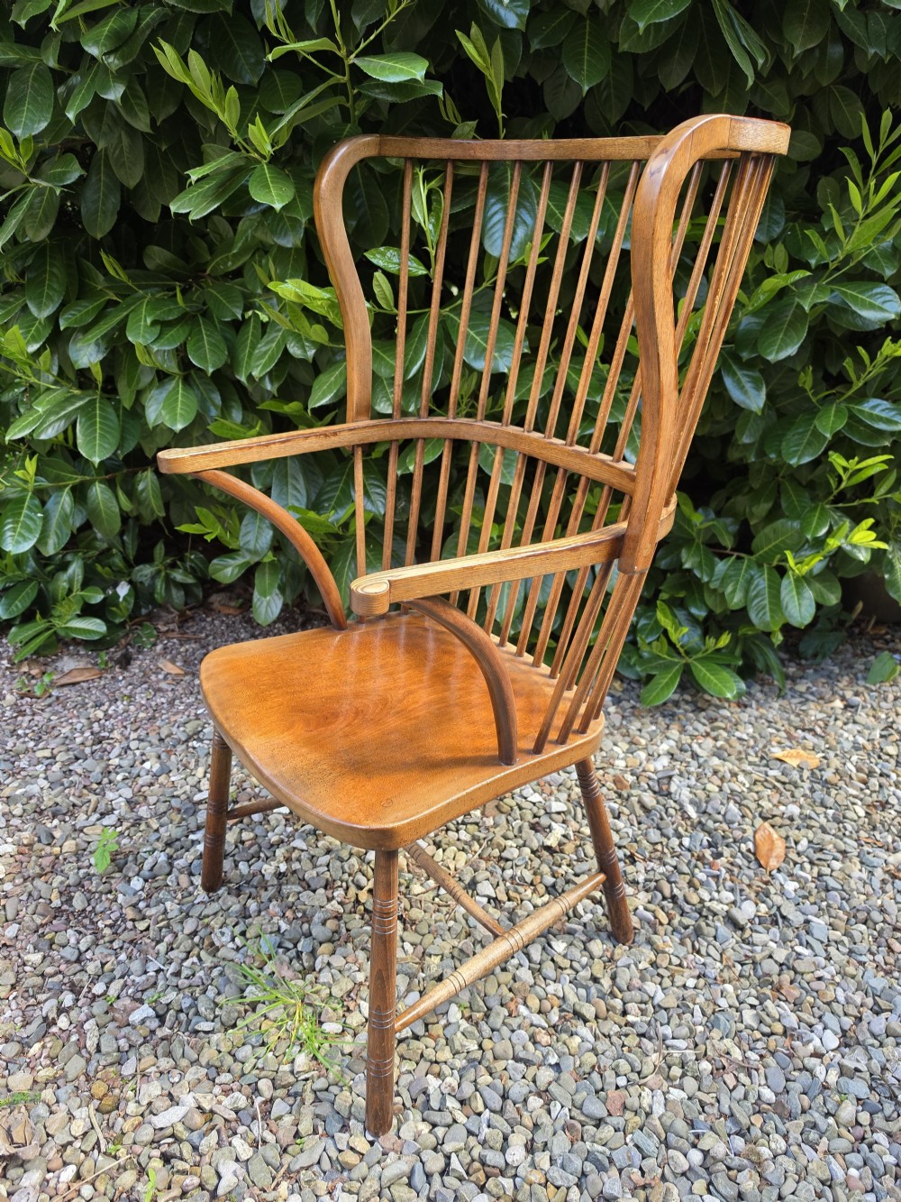 A late nineteenth-century ash and elm winged Windsor armchair featuring vertical back spindles, swept armrests, a shaped saddle seat, and turned wooden legs. View VI