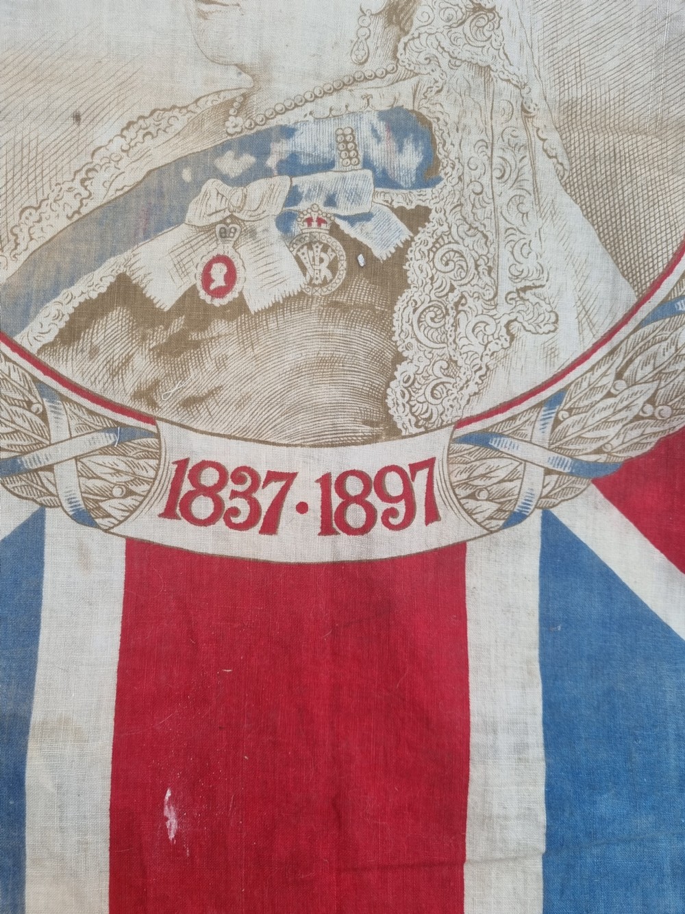 A square printed Union Jack flag featuring a central circular portrait of Queen Victoria inscribed with the dates 1837 to 1897. View V