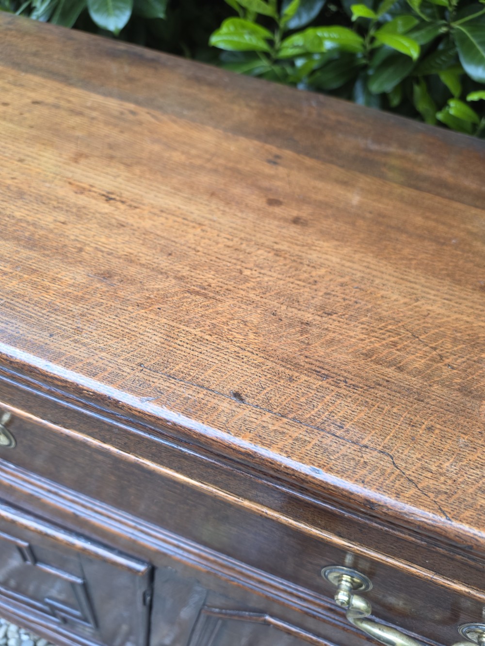 A Georgian dark oak dresser base featuring three top drawers over geometric moulded panel doors on bracket feet. View IV