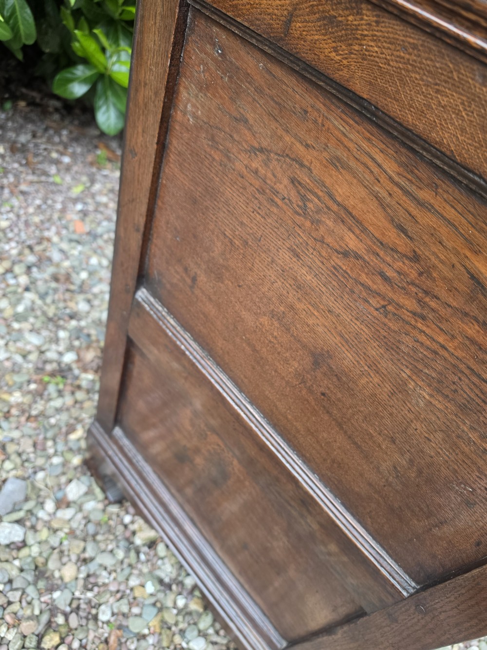 A Georgian dark oak dresser base featuring three top drawers over geometric moulded panel doors on bracket feet. View VI