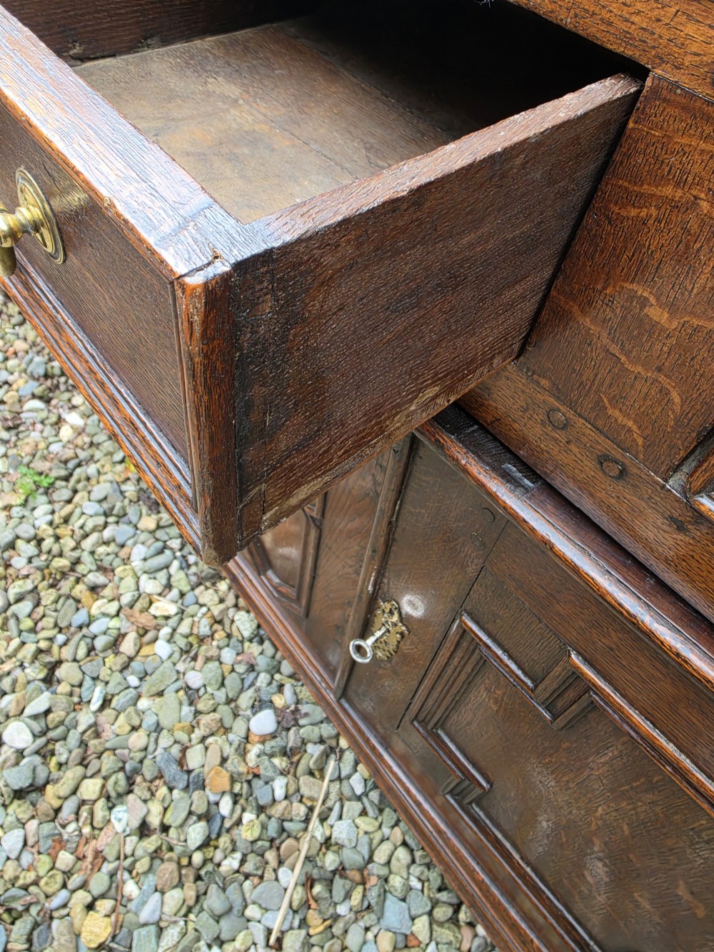 A Georgian dark oak dresser base featuring three top drawers over geometric moulded panel doors on bracket feet. View VII