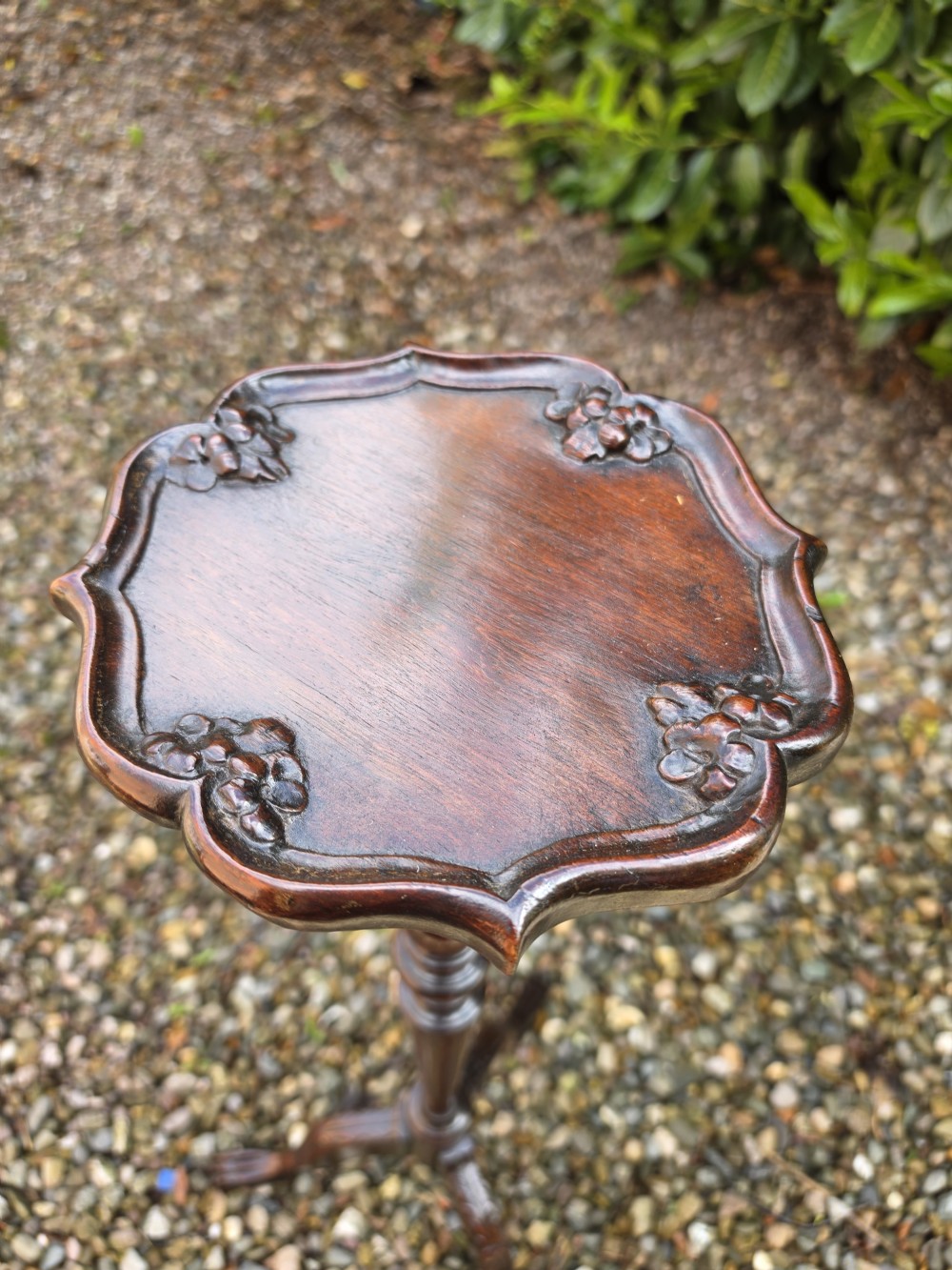 An Edwardian dark mahogany torchere stand featuring a carved piecrust top, turned stem, and tripod cabriole legs. View II