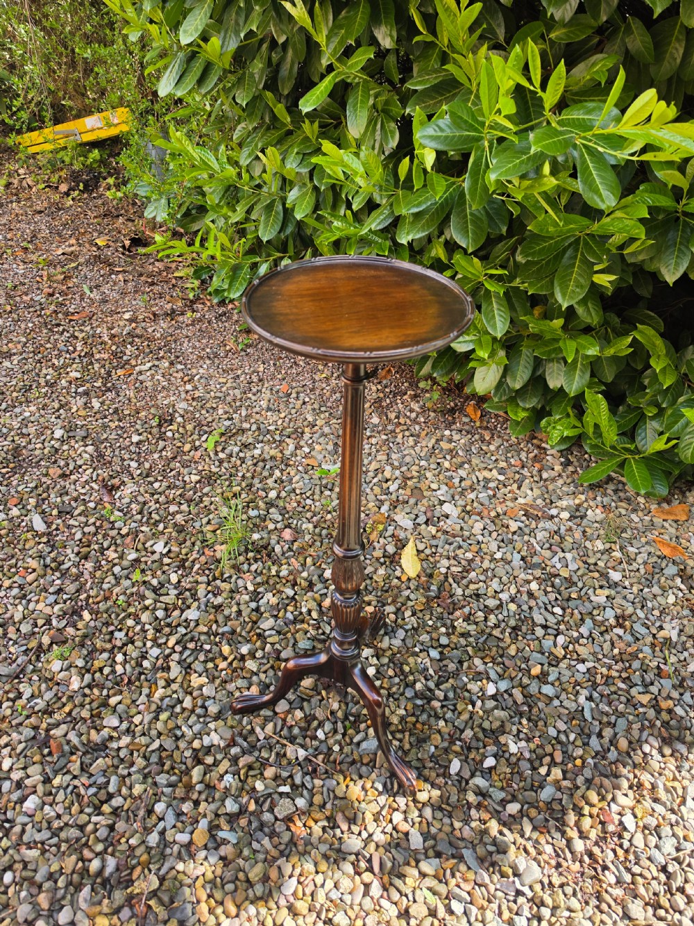 A tall mahogany plant stand with a circular dished top, reeded central column, and tripod cabriole legs ending in claw and ball feet.