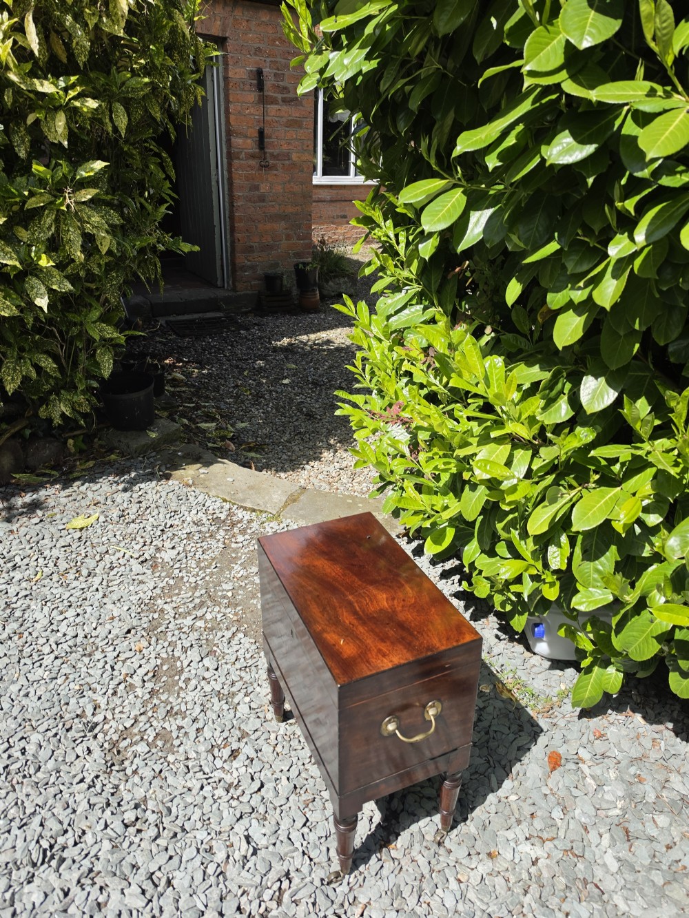 A dark Georgian mahogany cellaret chest featuring a flat hinged lid, central brass keyhole escutcheon, side carrying handles, and four turned legs. View VI