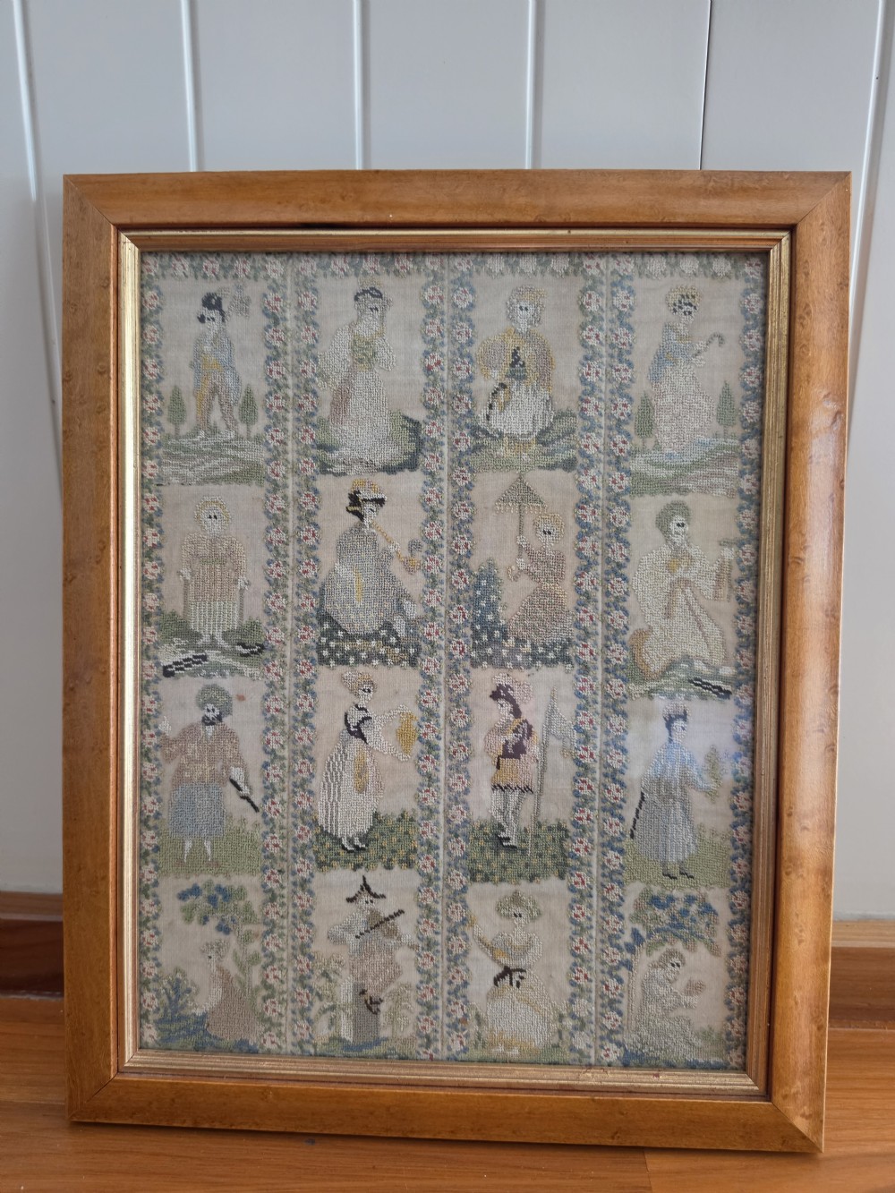 A framed Georgian silk needlework sampler featuring sixteen individual figures in historical costume, framed within floral column borders and a timber frame. View III