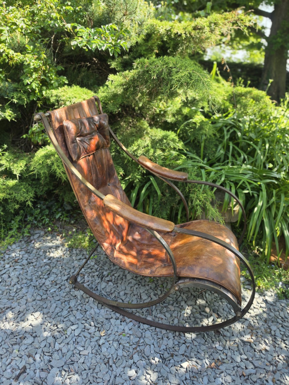 A Victorian metal frame rocking chair featuring a dark leather sling seat and an integrated buttoned headrest cushion. View II