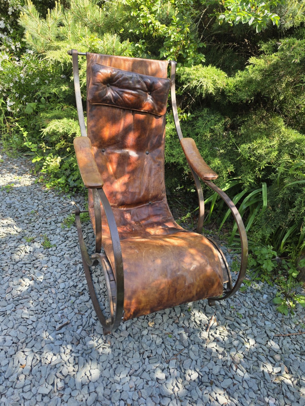 A Victorian metal frame rocking chair featuring a dark leather sling seat and an integrated buttoned headrest cushion. View IV