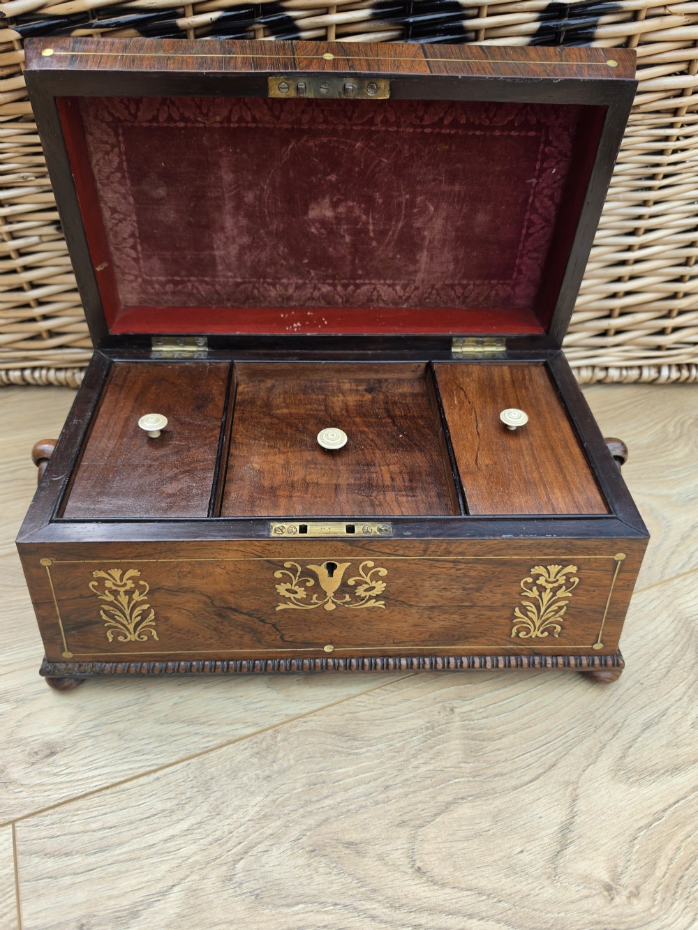 A Regency period dark rosewood tea caddy featuring ornate brass floral scrollwork inlay, gadrooned borders, and a central bird motif on the hinged lid. View IV