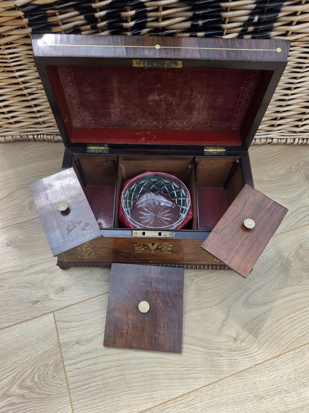 A Regency period dark rosewood tea caddy featuring ornate brass floral scrollwork inlay, gadrooned borders, and a central bird motif on the hinged lid. View V