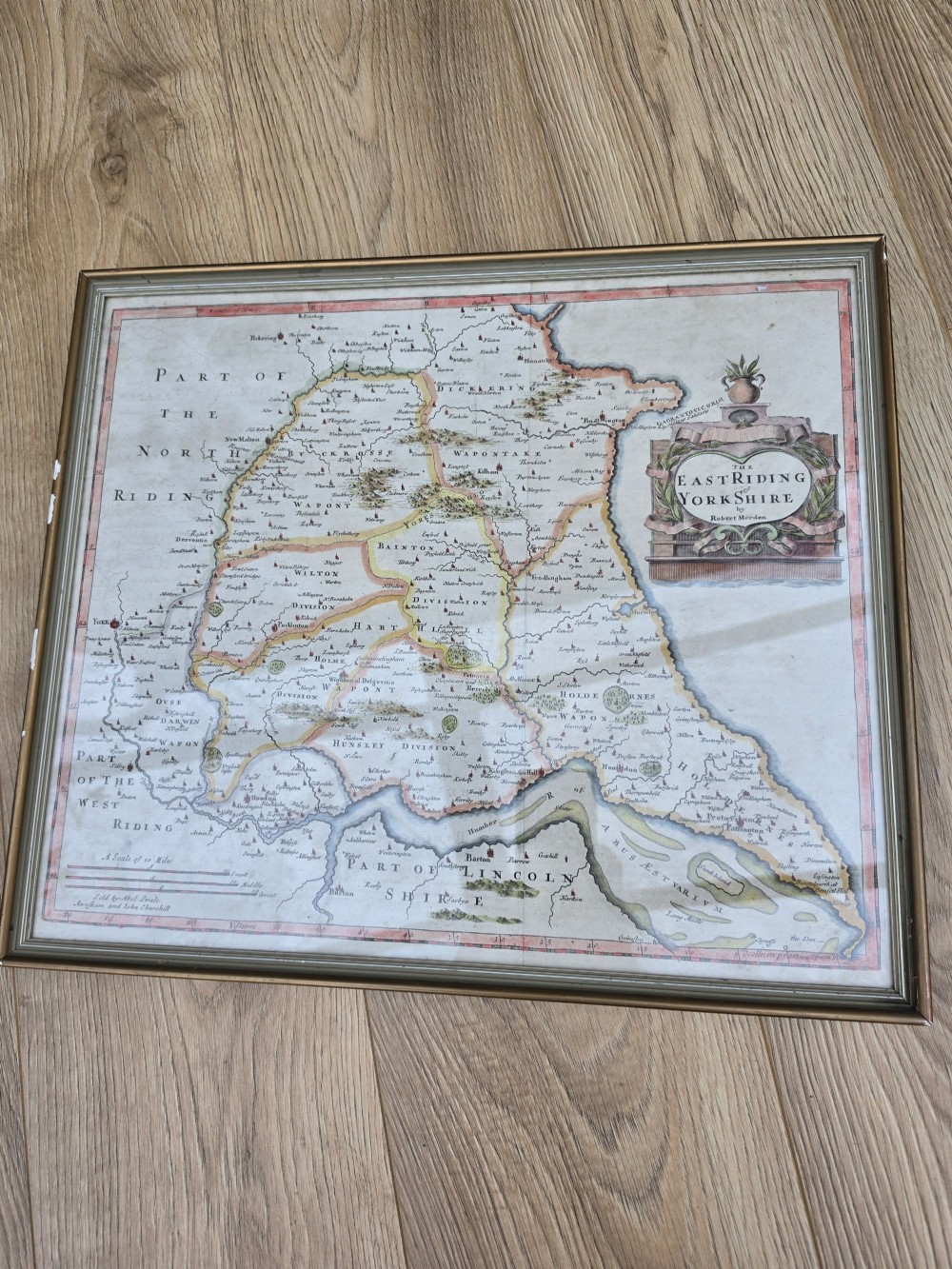 A framed 17th-century hand-coloured engraved map of the East Riding of Yorkshire featuring a decorative cartouche and thin gold border. View V