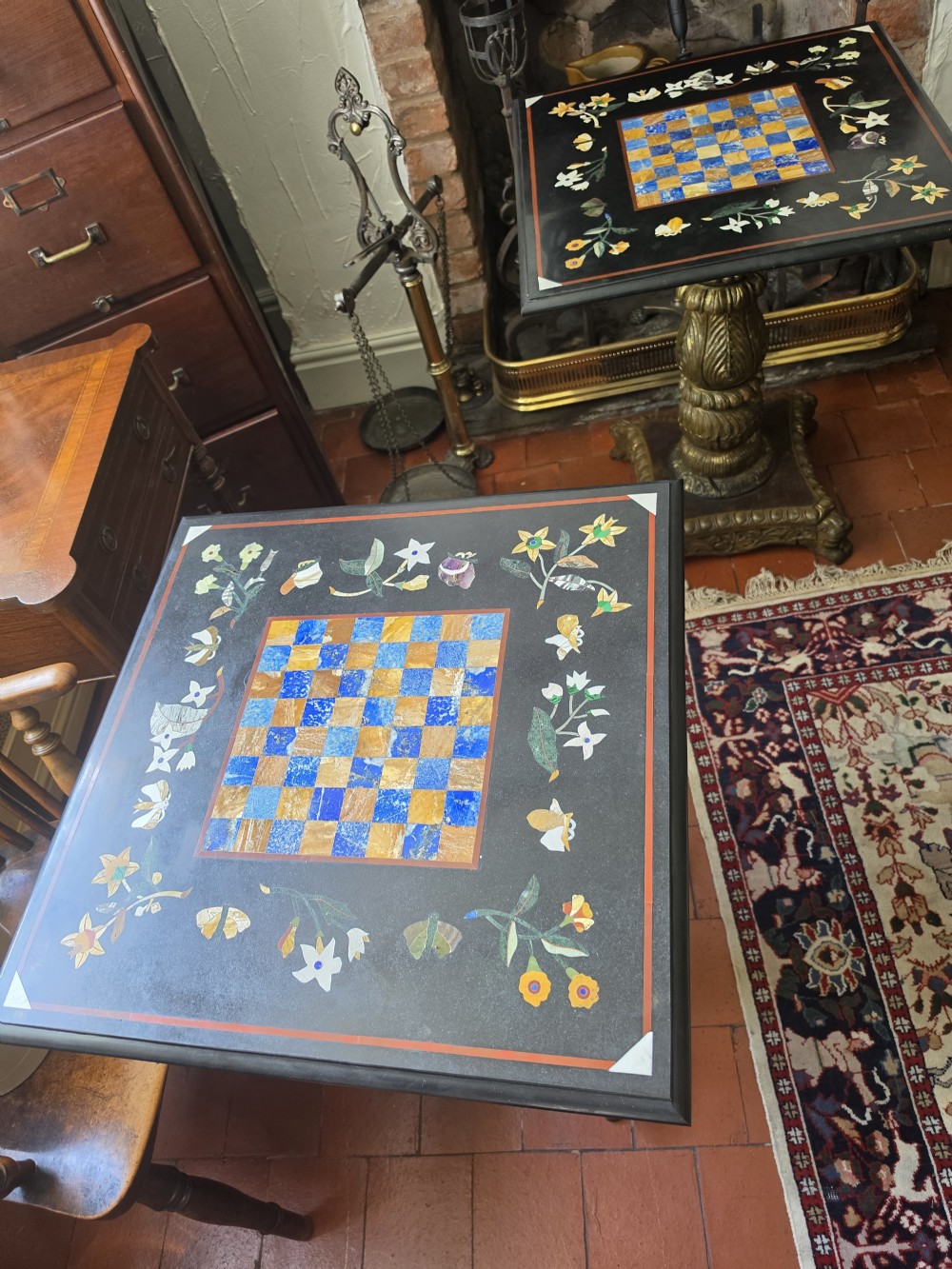 A pair of 19th-century occasional tables featuring square black marble tops inlaid with colourful pietra dura chessboard patterns and floral borders on carved giltwood pedestal bases. View II